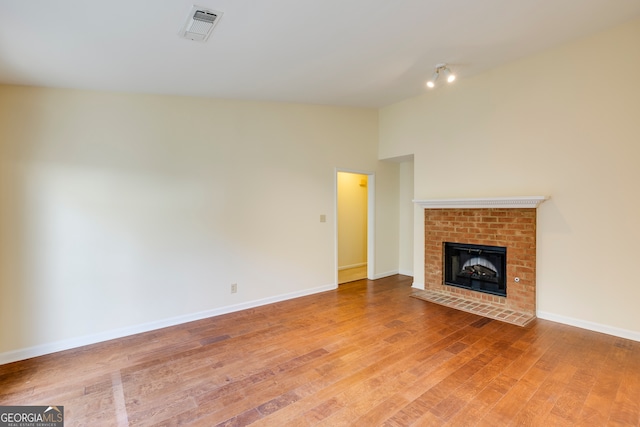 unfurnished living room with hardwood / wood-style floors and a brick fireplace