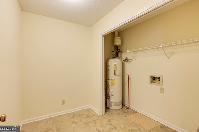 washroom with water heater, hookup for a washing machine, and a textured ceiling