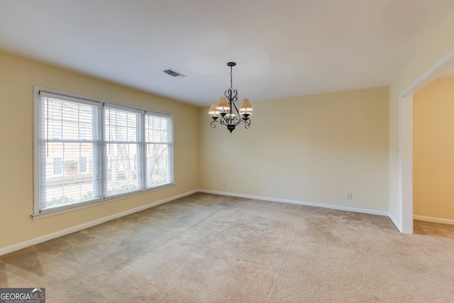 carpeted empty room with a notable chandelier