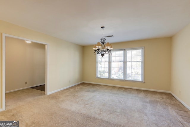 carpeted empty room featuring a chandelier