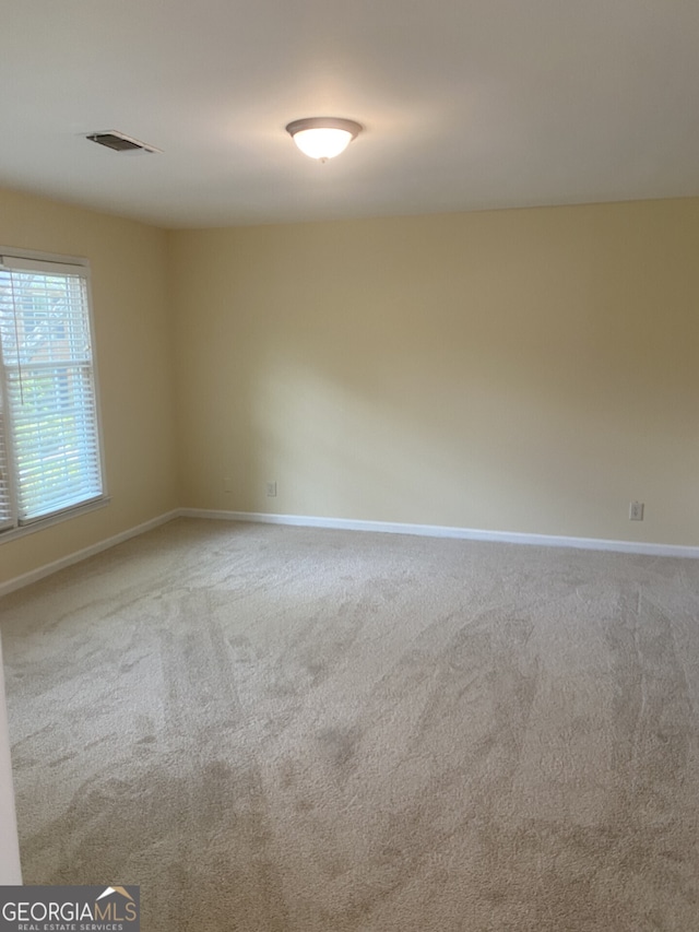 empty room with carpet floors, baseboards, and visible vents