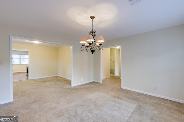 spare room featuring an inviting chandelier, baseboards, visible vents, and light colored carpet