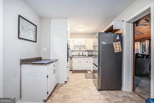 kitchen with ceiling fan, white cabinetry, sink, and stainless steel refrigerator