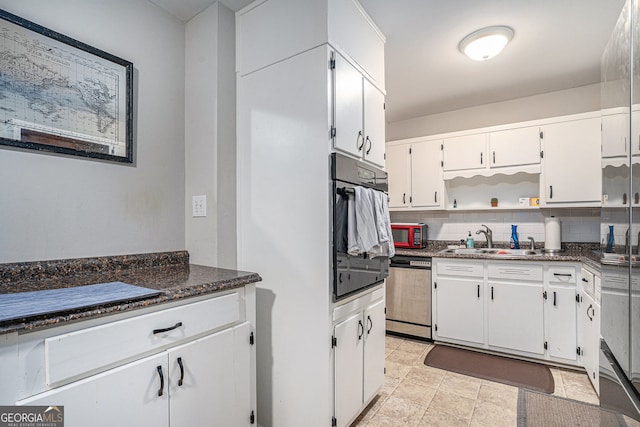 kitchen featuring dark stone counters, black appliances, white cabinets, sink, and decorative backsplash