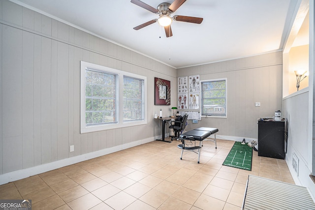 tiled home office featuring wooden walls, crown molding, and ceiling fan