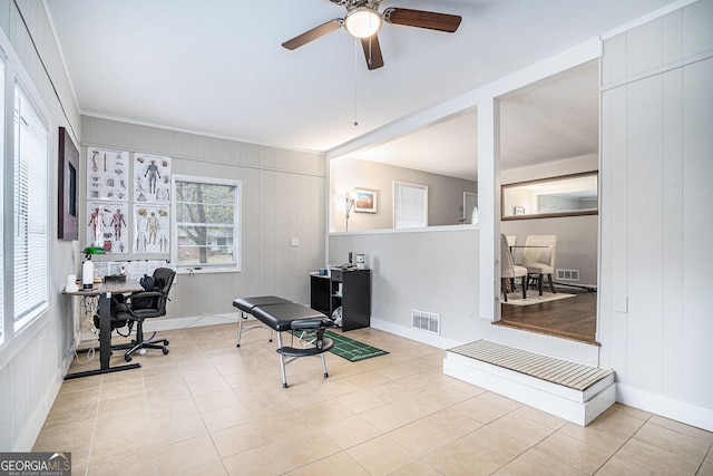 office space with wood walls, plenty of natural light, ceiling fan, and light tile patterned floors