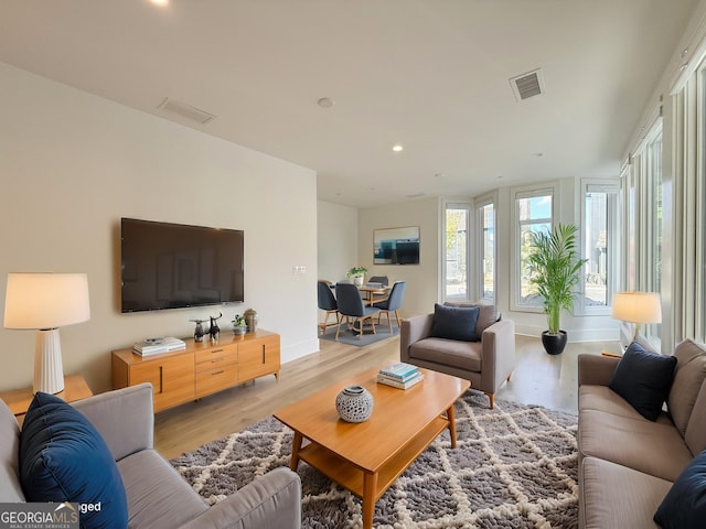 living room with recessed lighting, visible vents, baseboards, and light wood-style flooring