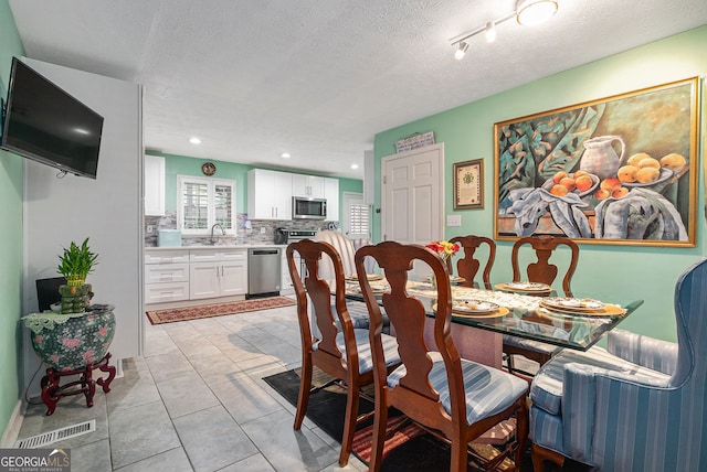 dining area with light tile patterned floors, a textured ceiling, and sink