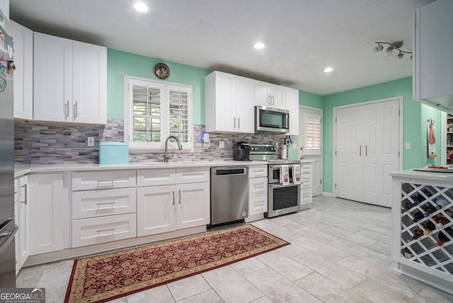 kitchen with white cabinets, decorative backsplash, stainless steel appliances, and sink