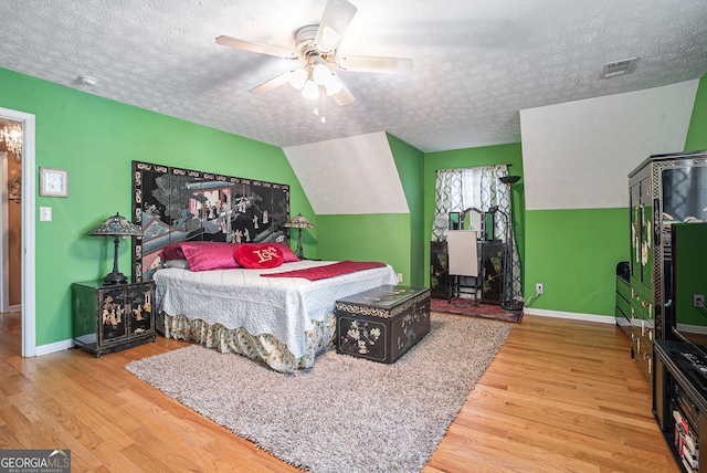 bedroom featuring hardwood / wood-style floors, a textured ceiling, ceiling fan, and lofted ceiling