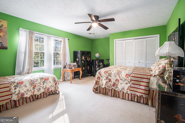 carpeted bedroom featuring a textured ceiling, a closet, and ceiling fan