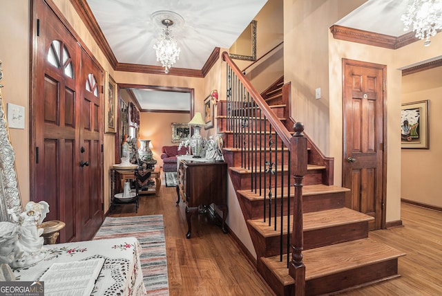 foyer featuring hardwood / wood-style floors, an inviting chandelier, and crown molding