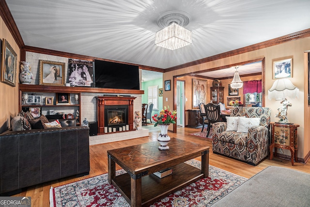 living room featuring a notable chandelier, wood-type flooring, a fireplace, and ornamental molding