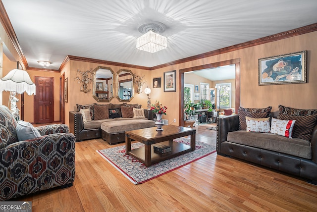 living room with wood-type flooring, ornamental molding, and a notable chandelier