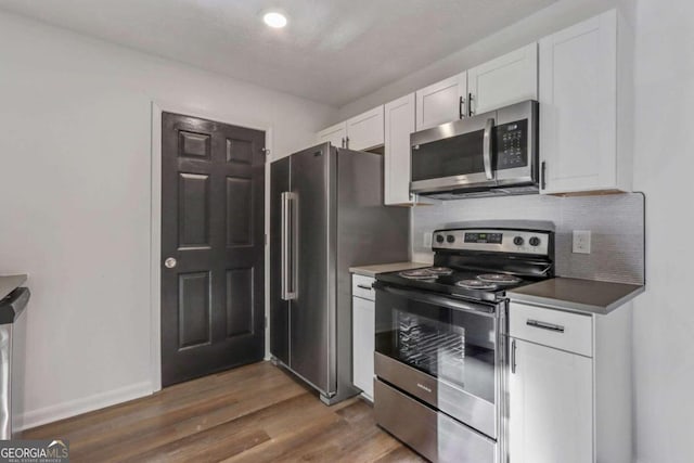 kitchen with white cabinets, backsplash, dark hardwood / wood-style flooring, and stainless steel appliances