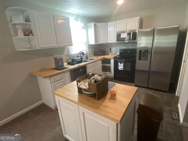 kitchen featuring black appliances, sink, tasteful backsplash, butcher block countertops, and white cabinetry