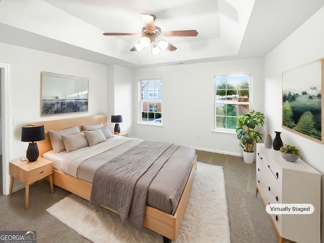 carpeted bedroom featuring a raised ceiling and ceiling fan