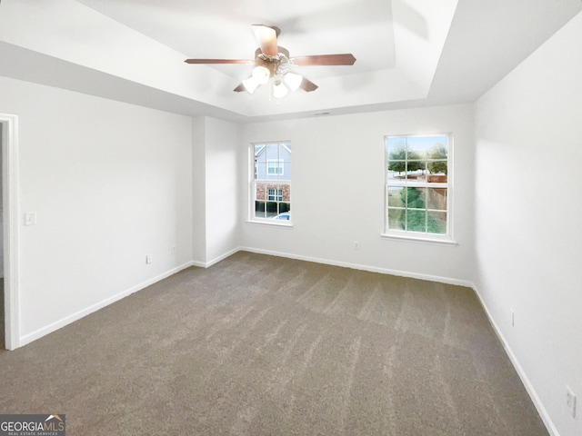 empty room featuring carpet, ceiling fan, and a tray ceiling