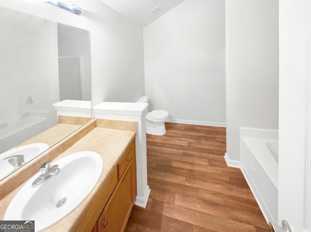 bathroom featuring a tub, vanity, wood-type flooring, and toilet