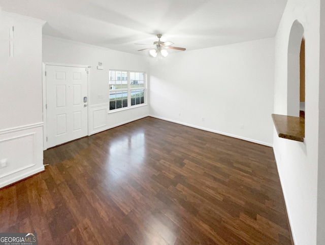 unfurnished living room featuring ceiling fan and dark wood-type flooring