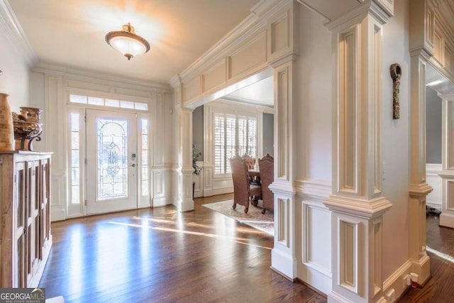 foyer entrance featuring crown molding, dark wood-type flooring, and ornate columns