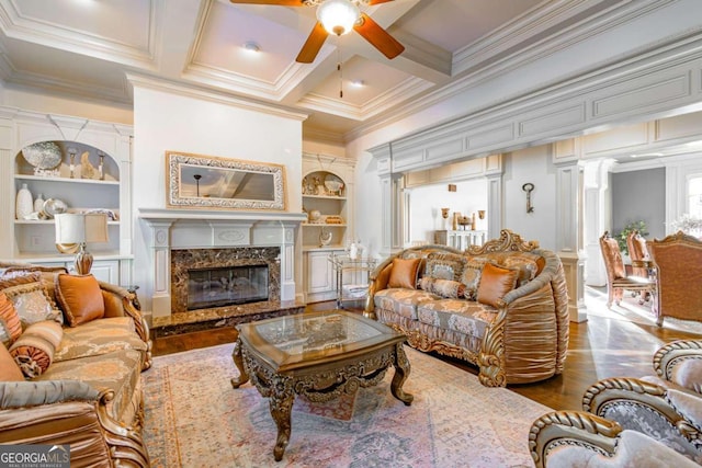 living room with built in shelves, crown molding, hardwood / wood-style floors, and a premium fireplace