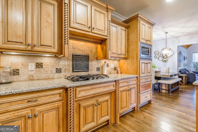 kitchen with hanging light fixtures, light wood-type flooring, appliances with stainless steel finishes, a notable chandelier, and light stone counters