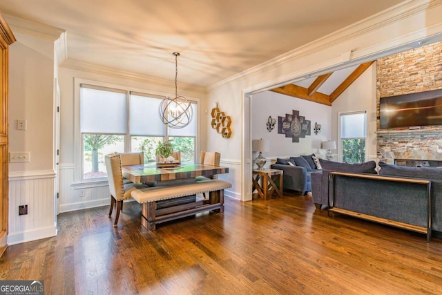 dining space featuring lofted ceiling, crown molding, dark hardwood / wood-style floors, a fireplace, and a notable chandelier