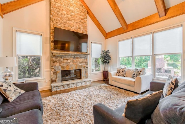 living room with beam ceiling, a fireplace, hardwood / wood-style floors, and high vaulted ceiling