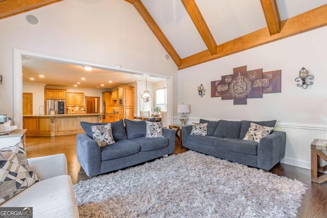 living room with beam ceiling, high vaulted ceiling, light hardwood / wood-style flooring, and sink