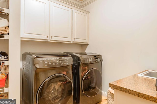 laundry room with cabinets, washing machine and dryer, crown molding, and sink