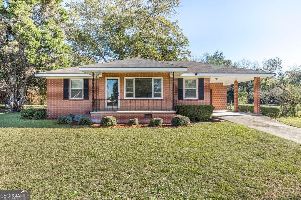 ranch-style home featuring a carport and a front lawn