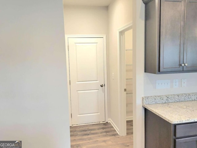 interior space featuring dark brown cabinetry, light stone countertops, and light hardwood / wood-style floors