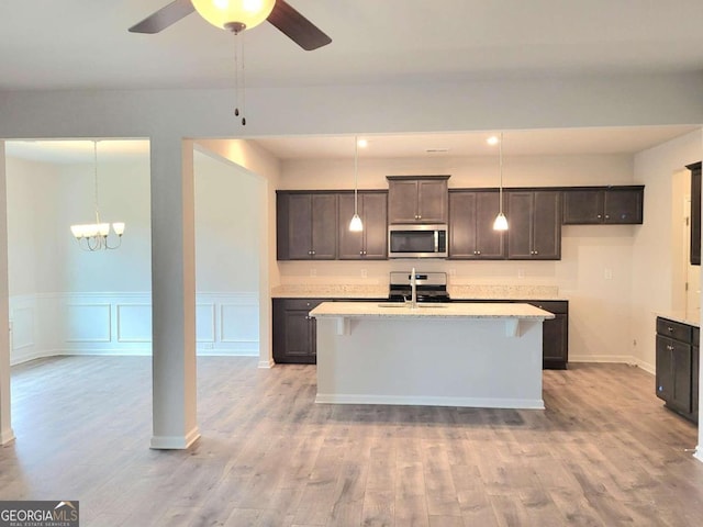 kitchen featuring pendant lighting, light wood-type flooring, stainless steel appliances, and a kitchen island with sink