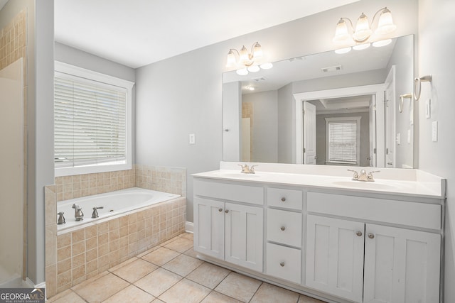 bathroom with tiled tub, tile patterned flooring, and vanity