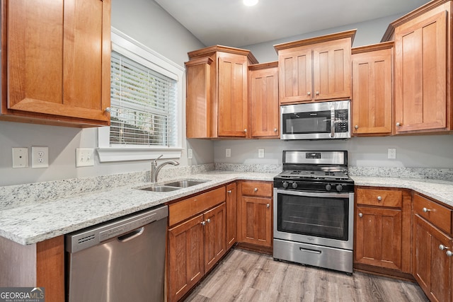 kitchen featuring sink, light stone countertops, stainless steel appliances, and light hardwood / wood-style flooring