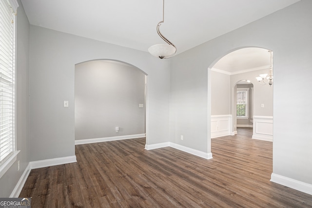 empty room featuring dark hardwood / wood-style floors, an inviting chandelier, and ornamental molding