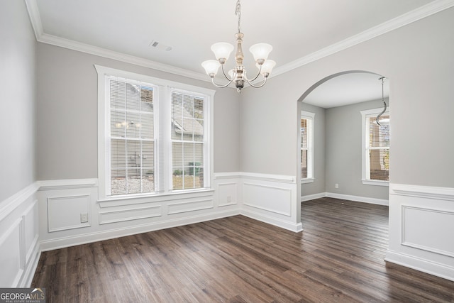 unfurnished dining area with dark hardwood / wood-style floors, a healthy amount of sunlight, crown molding, and an inviting chandelier