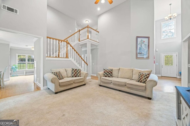 living room featuring a towering ceiling, ceiling fan with notable chandelier, and hardwood / wood-style flooring