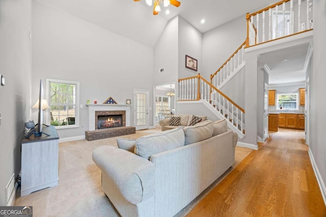 living room featuring ceiling fan, a fireplace, high vaulted ceiling, and light hardwood / wood-style floors