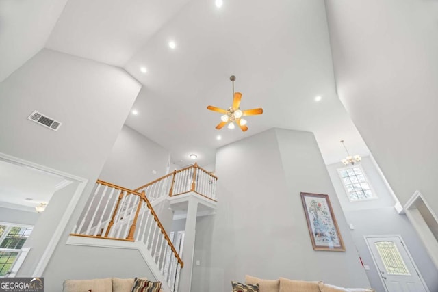 stairway with ceiling fan with notable chandelier and a high ceiling