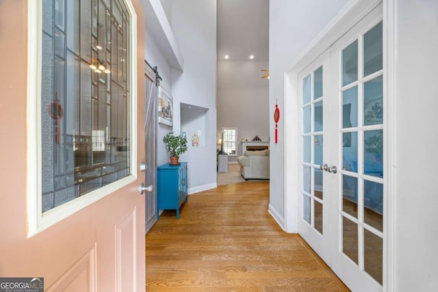 corridor featuring a barn door, french doors, and light hardwood / wood-style flooring