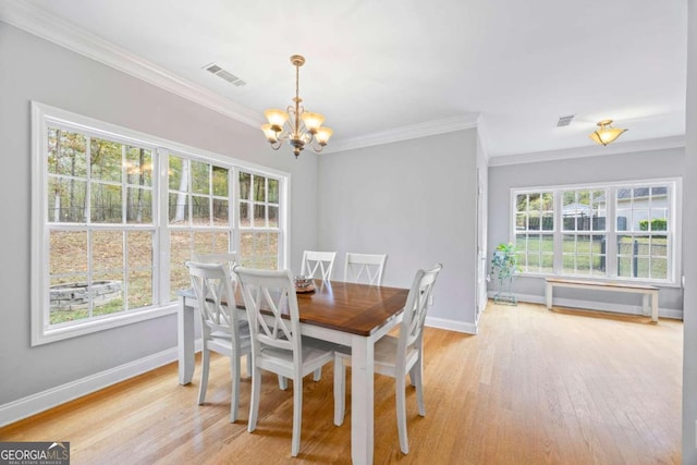 dining area with plenty of natural light, ornamental molding, a chandelier, and light hardwood / wood-style flooring