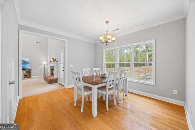 dining space featuring crown molding, light hardwood / wood-style flooring, and a chandelier