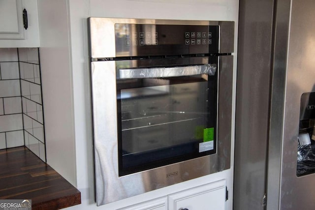 interior details with white cabinetry and stainless steel refrigerator