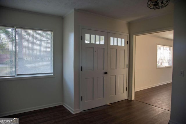 foyer with a textured ceiling, ornamental molding, and dark wood-type flooring