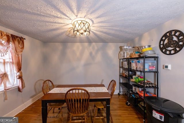 dining space featuring wood-type flooring, a textured ceiling, and a notable chandelier