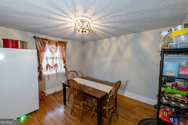 dining space with wood-type flooring and a textured ceiling