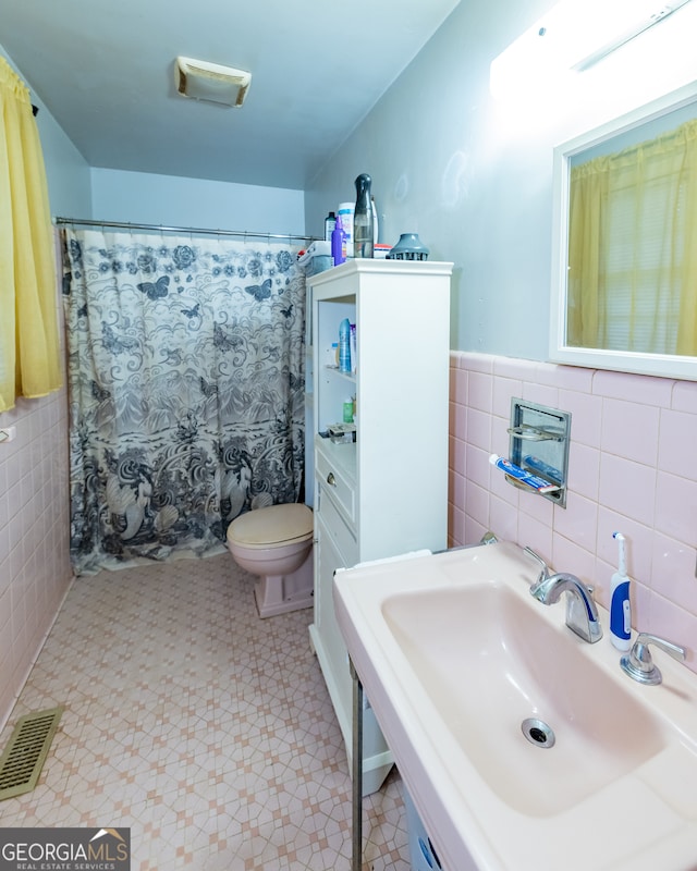 bathroom with toilet, tile walls, and sink