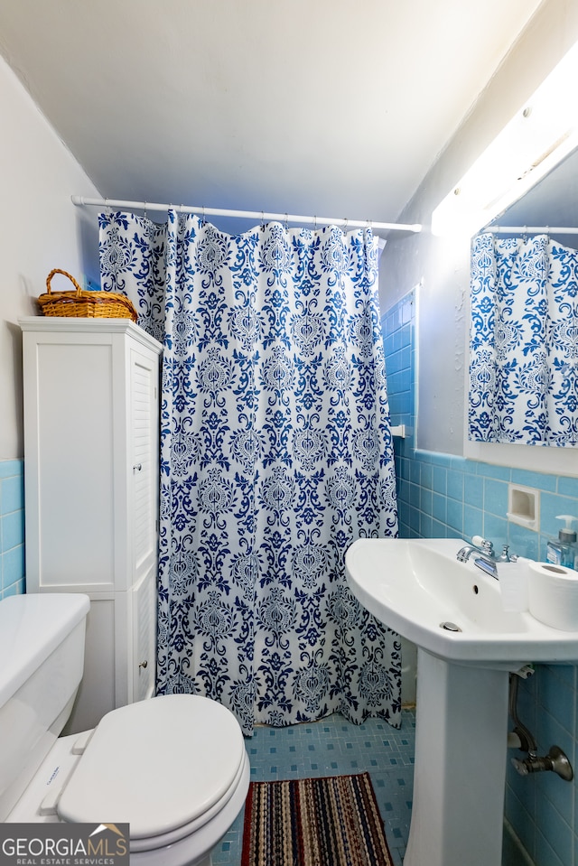 bathroom with curtained shower, tile patterned flooring, tile walls, and toilet